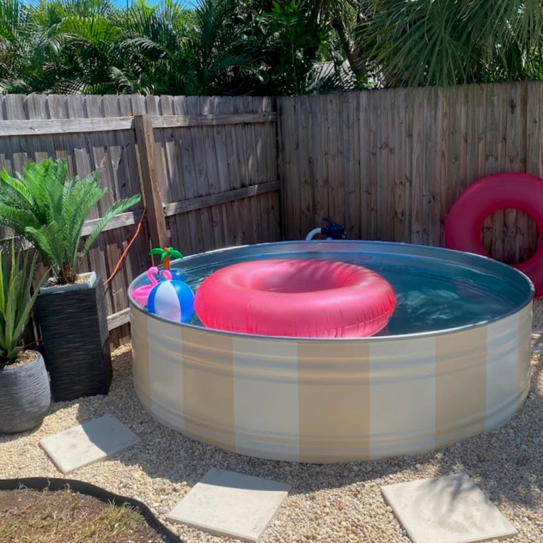 Metallic above-ground pool with inflatable rings and toys in a backyard setting.