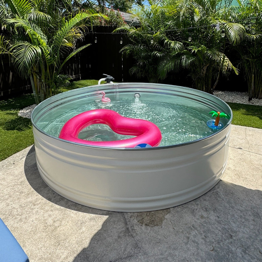 Small above-ground pool with a pink heart-shaped float and palm tree toy on a patio.