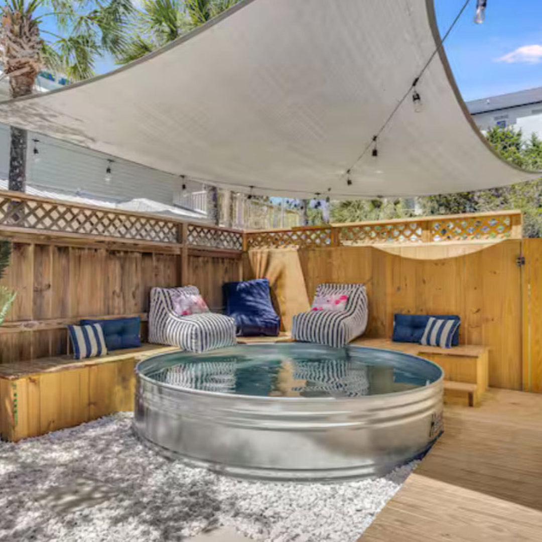 Outdoor patio area with a metal tub, chairs, and a canopy on a sunny day.