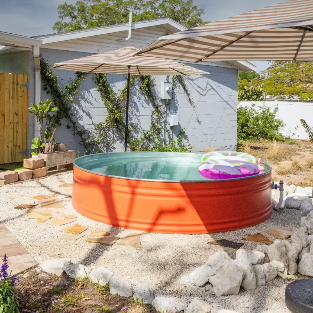 Red and orange above-ground pool in a backyard with a patio and umbrella.