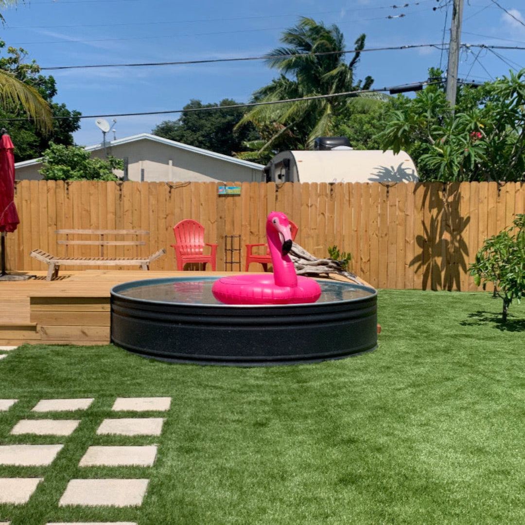 Backyard with inflatable flamingo pool toy, wooden deck, and grassy area.