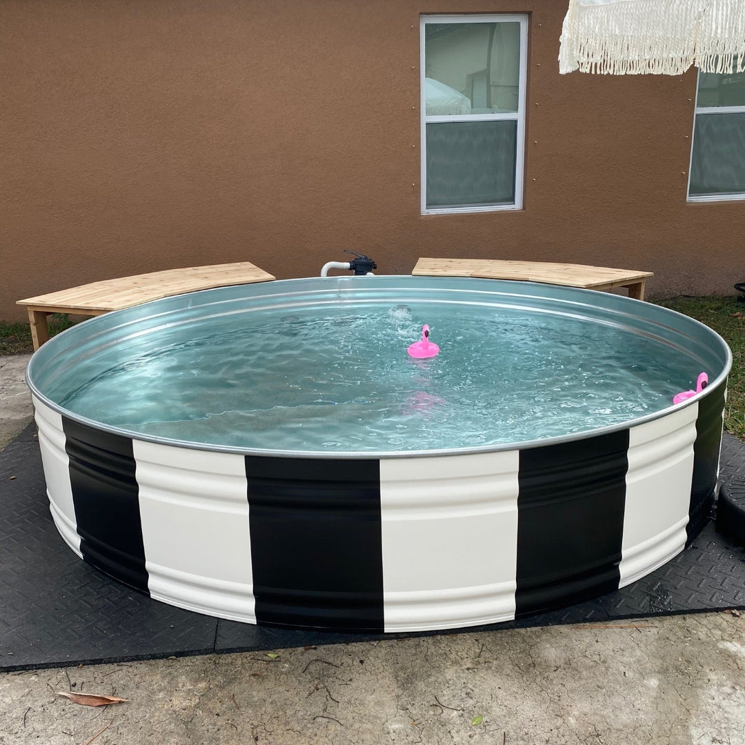 Portable above-ground pool with black and white striped base in a backyard setting.