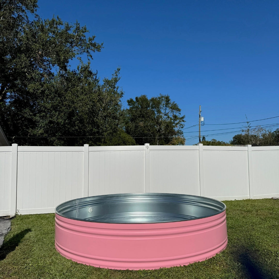 Pink metal tank on grass with trees and blue sky in the background