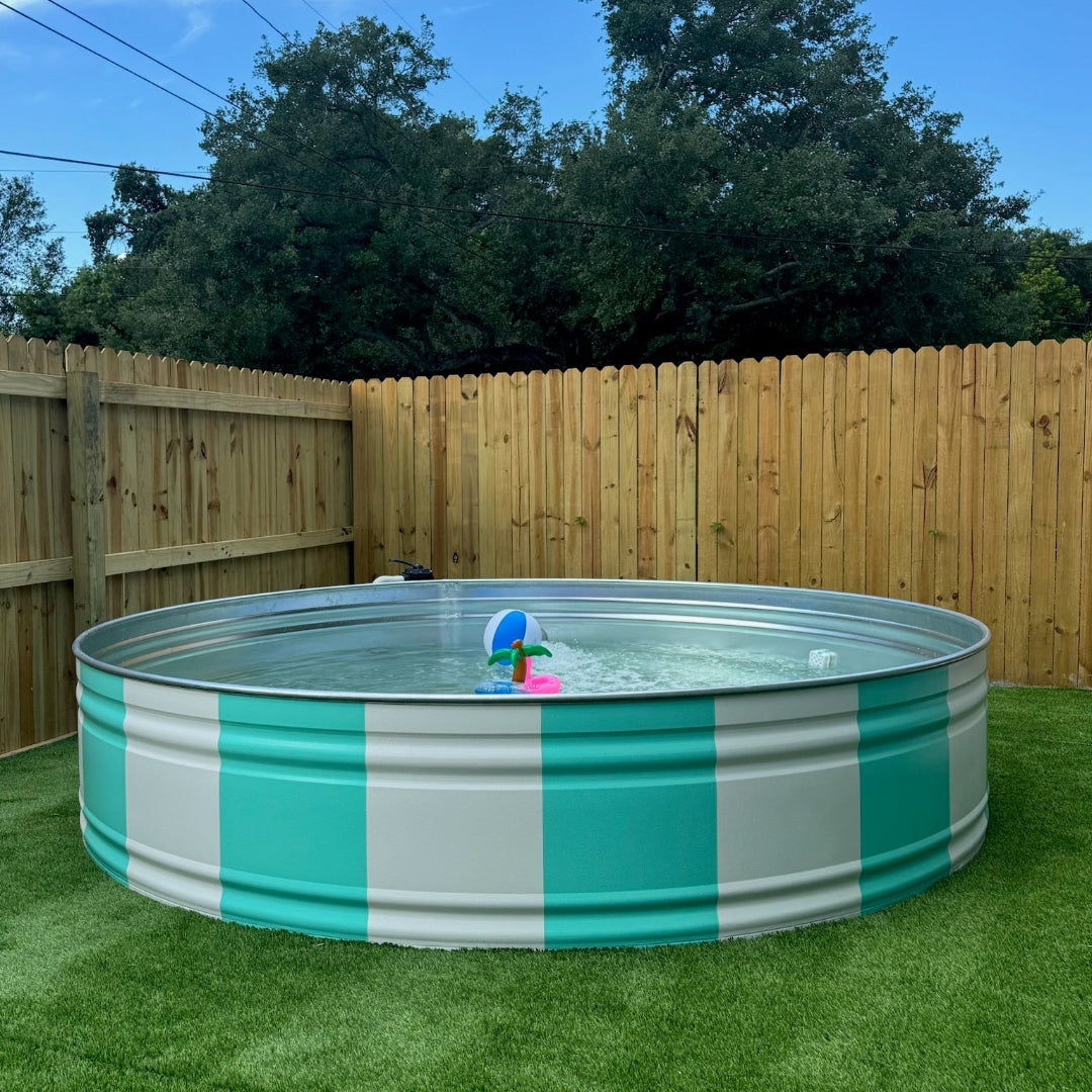 Round above-ground pool with striped design on grass, surrounded by a wooden fence and trees.