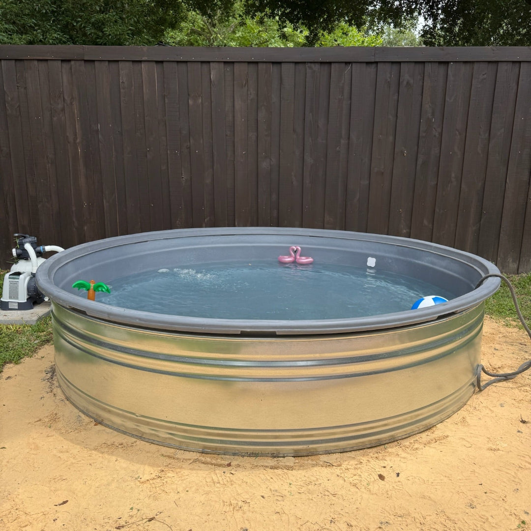 Metal water tank converted into a pool with toys in a backyard setting.
