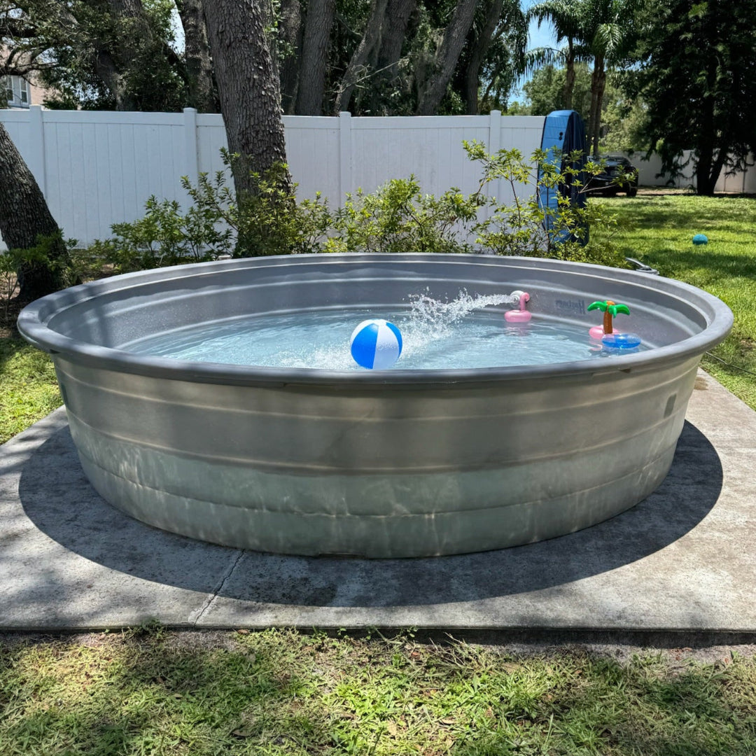 Metallic above-ground pool in a backyard with children's toys and a tree in the background.