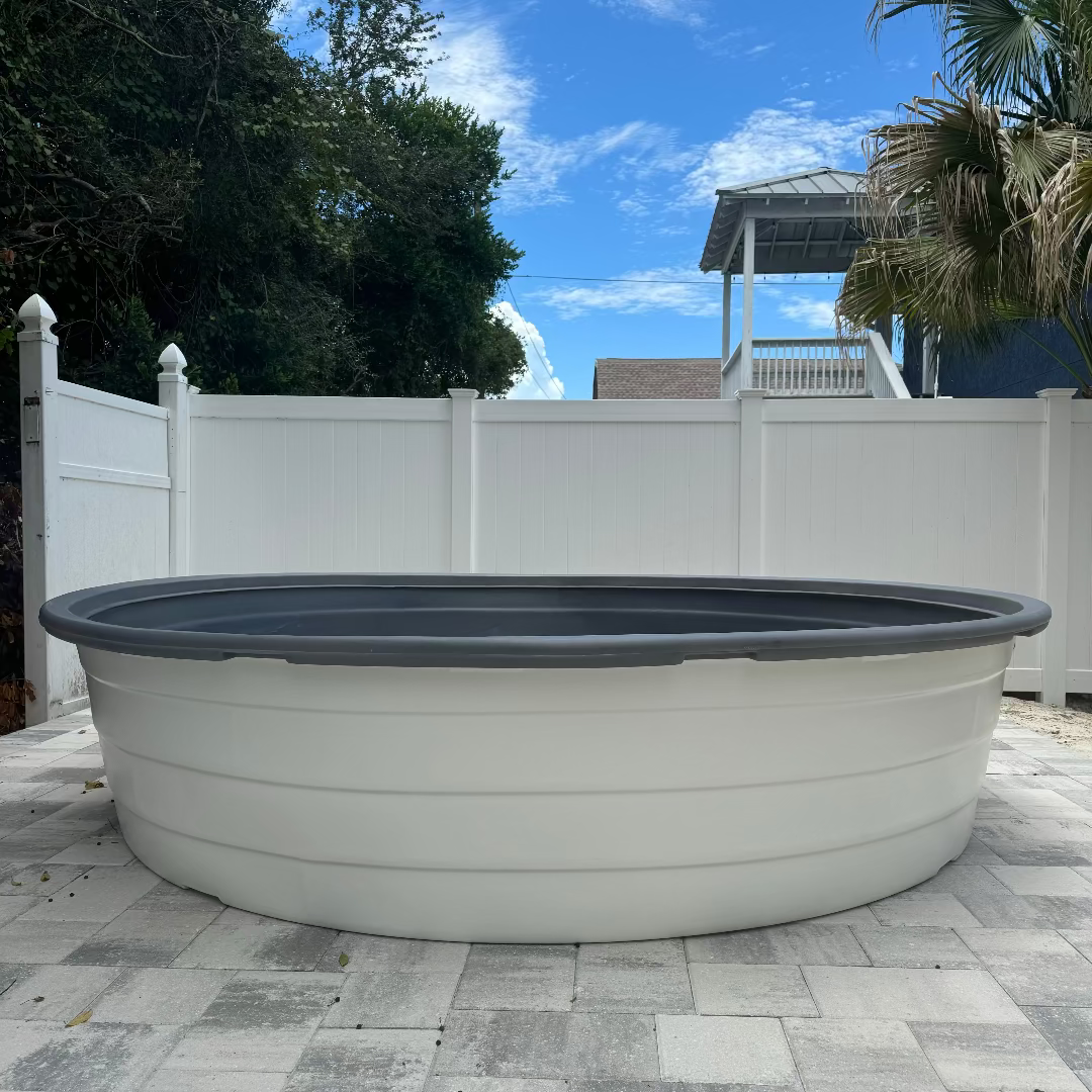Large above-ground pool on a patio with trees and a white fence in the background