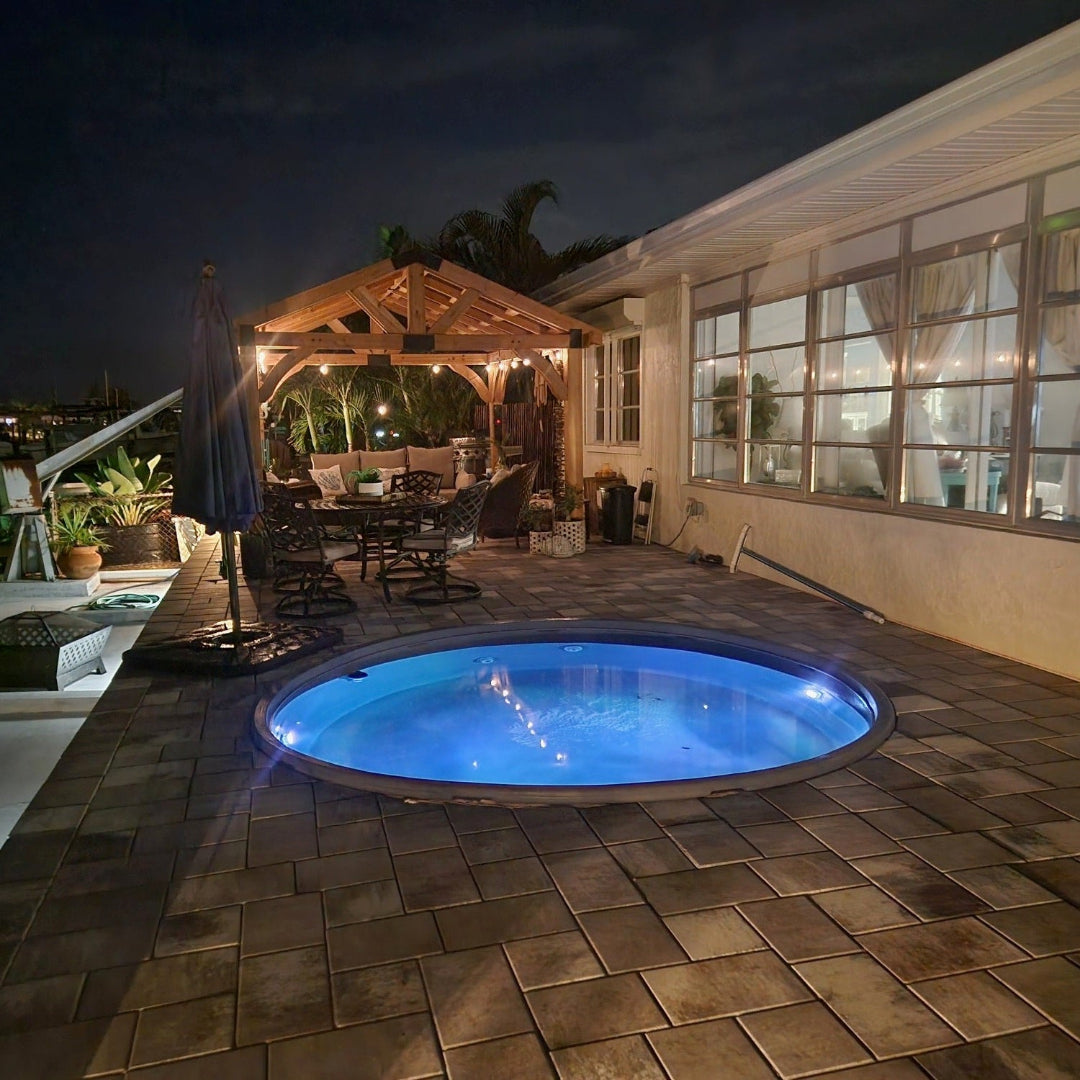 Outdoor patio area with a hot tub at night