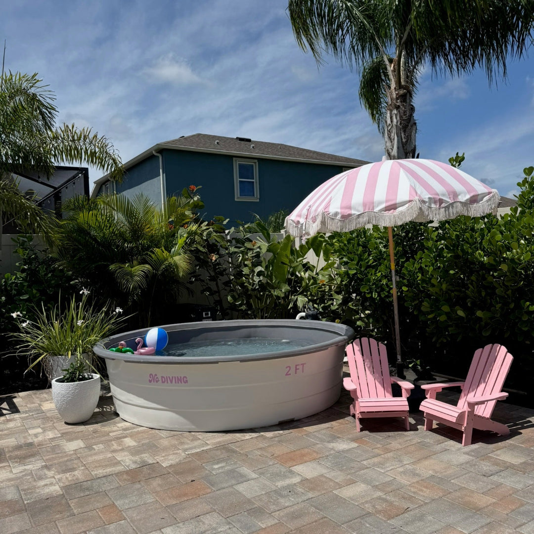 Portable hot tub on a patio with pink chairs and an umbrella in a backyard setting.
