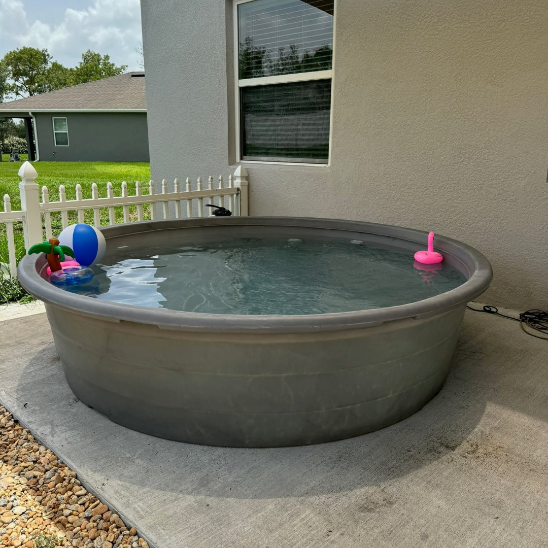 Small above-ground pool with inflatable toys on a concrete patio outside a house.