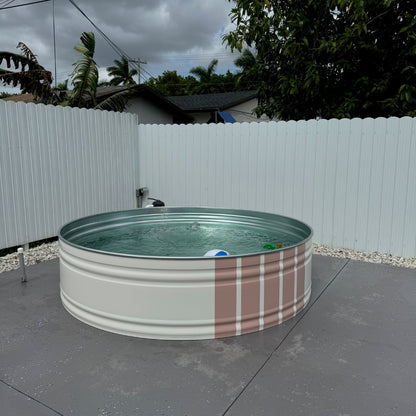 Small round pool with plaid design on a concrete surface, surrounded by a white fence and trees.