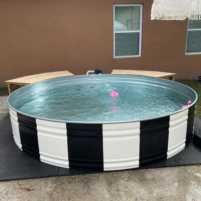Portable above-ground pool with black and white striped base in a backyard setting.
