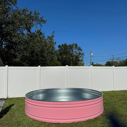 Pink metal tank on grass with trees and blue sky in the background