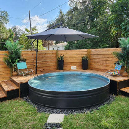 Small round pool in a backyard with wooden deck, chairs, and plants.
