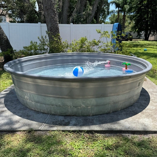 Metallic above-ground pool in a backyard with children's toys and a tree in the background.