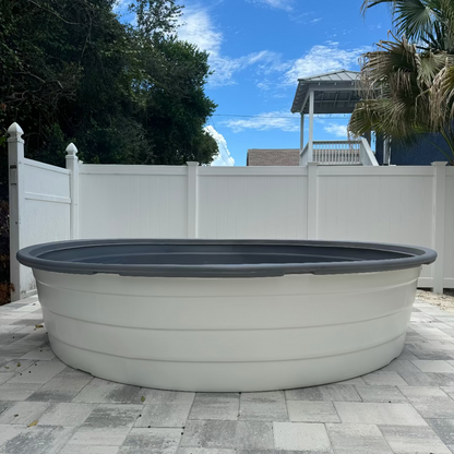 Large above-ground pool on a patio with trees and a white fence in the background